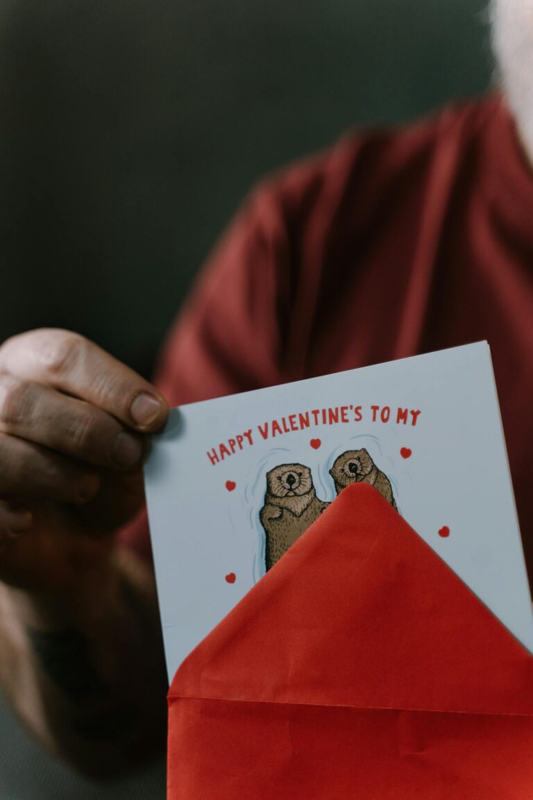 Close-up of a person holding a cute Valentine's card with groundhogs in a red envelope.