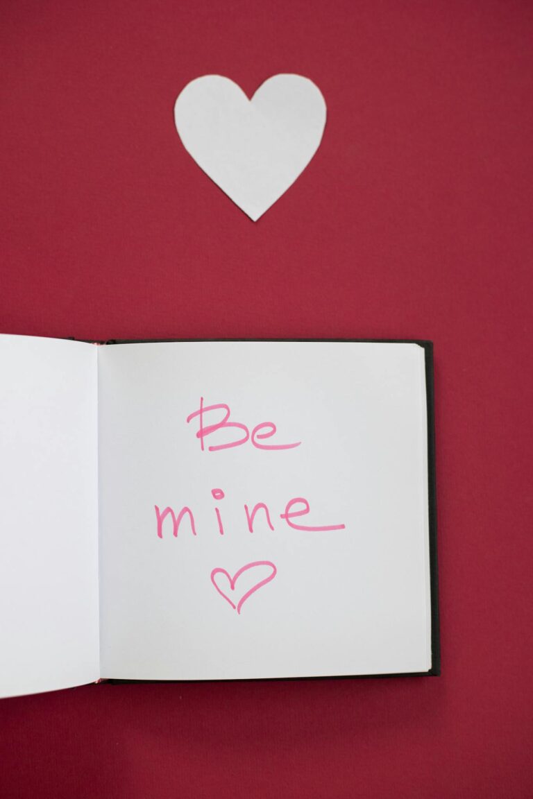 Explore love with this open notebook and heart symbol on a red background.