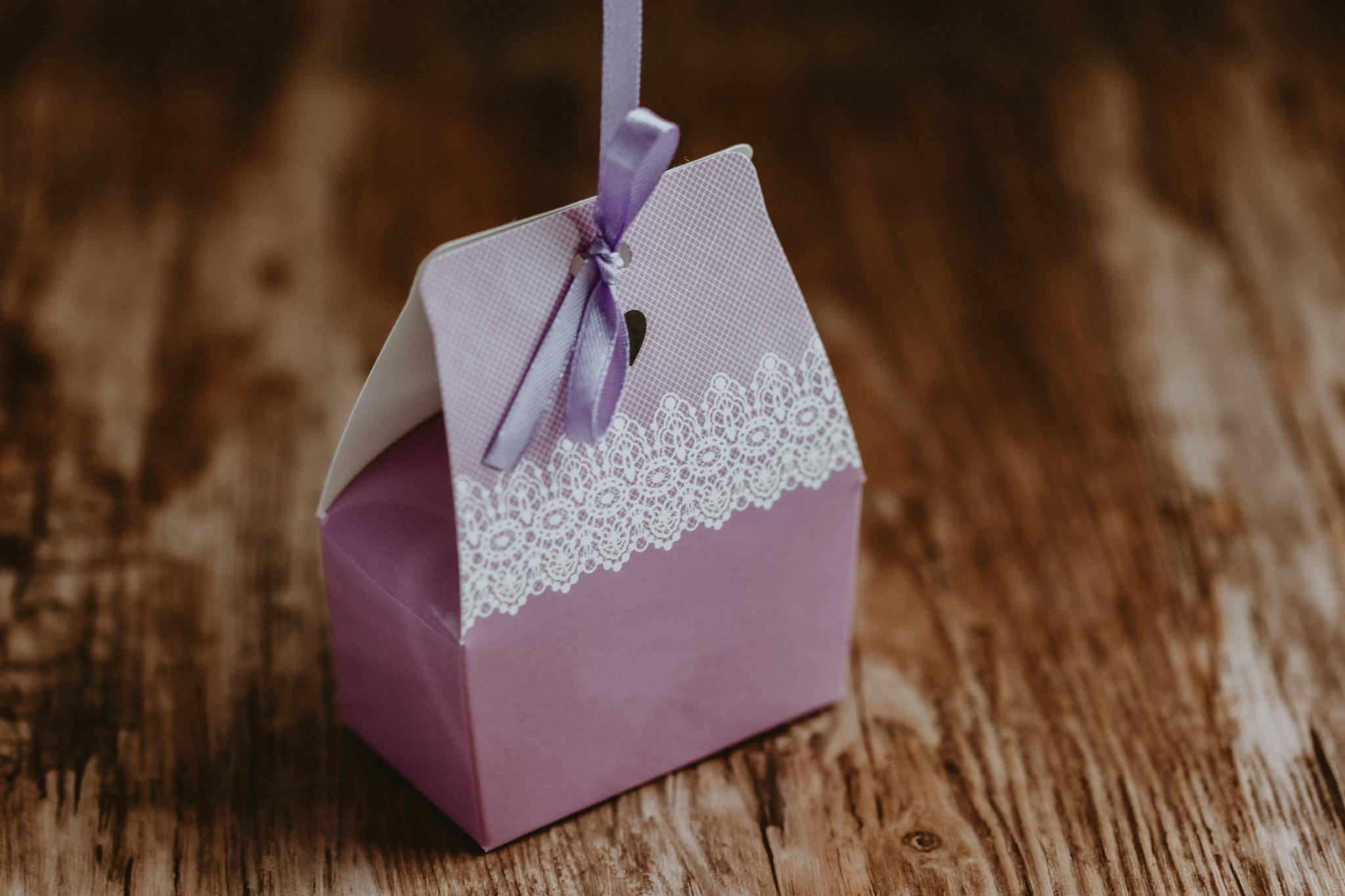Purple gift box with lace detail and ribbon on rustic wooden table. Perfect for special occasions.